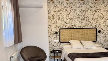 A bedroom with a bed, a chair, a small table, and a radiator.