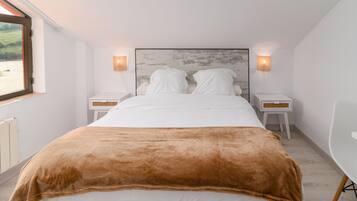 A bedroom with a large bed, two bedside tables, a nightstand, a window, and a view of the outdoors.