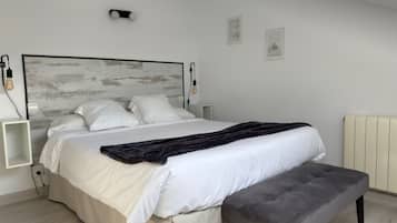 Un dormitorio moderno con cama, mesitas de noche, un banco y un radiador.