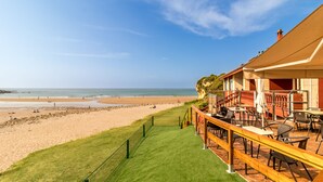 A beachfront hotel with a grassy patio, outdoor seating, and a view of the beach and ocean. - Hotel Sanmar (Alfoz de Lloredo)