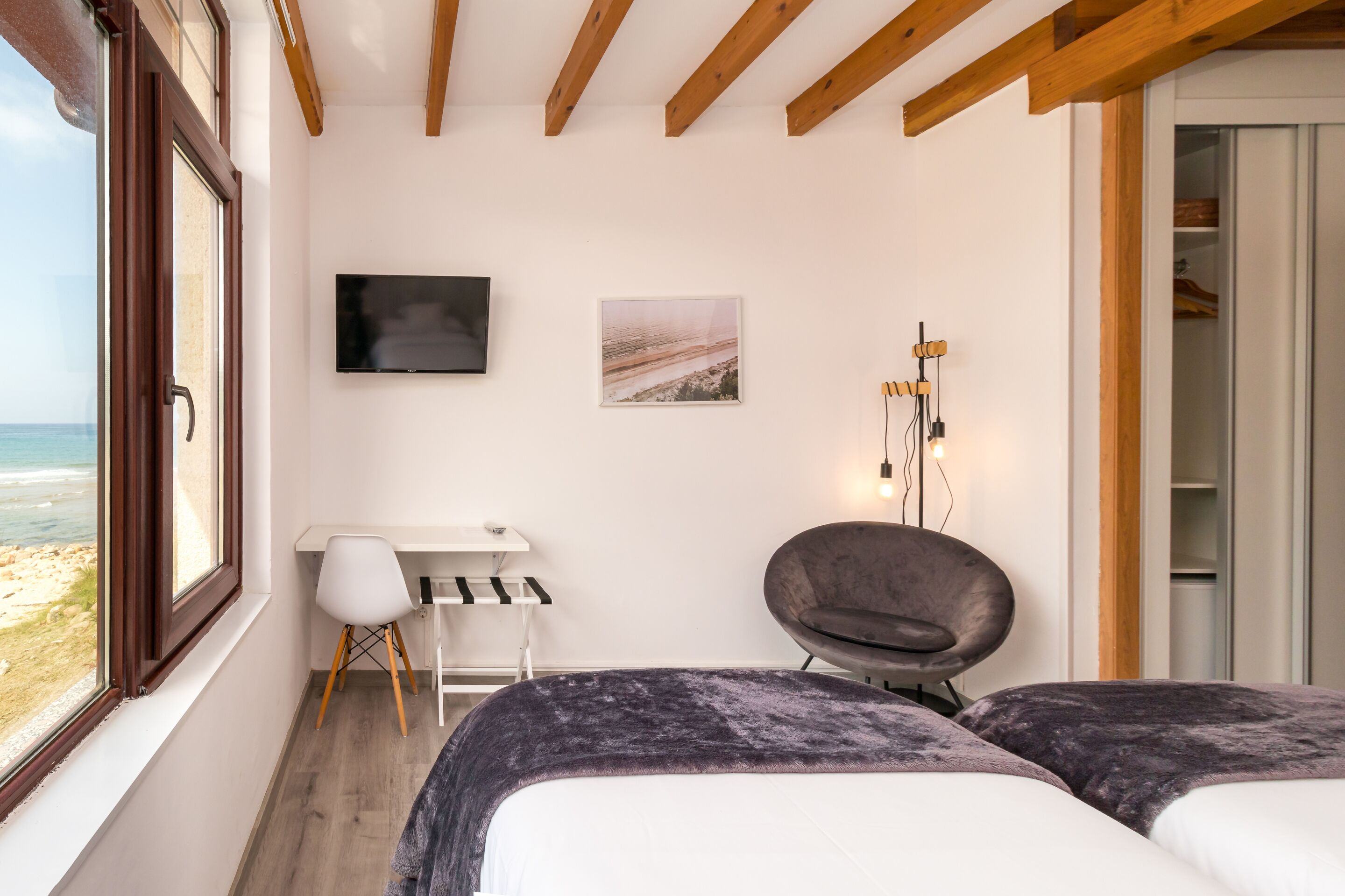 A bedroom with a bed, a desk, a chair, a TV, and a wardrobe.