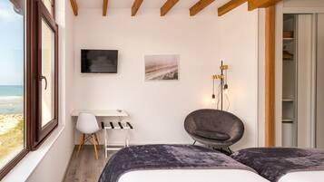 A bedroom with a bed, a desk, a chair, a TV, and a wardrobe.