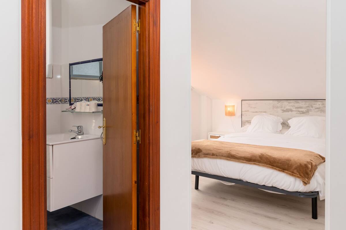 Een slaapkamer met een bed, nachtkastje en een klein tafeltje.