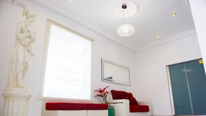 Een modern interieur met een witte bank, een beeld, een groot raam en een deur.