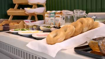 A breakfast buffet with bagels, various spreads, and milk cartons.