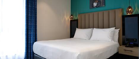 Une chambre d’hôtel moderne avec un grand lit, une table de chevet avec un téléphone et un tableau au mur.