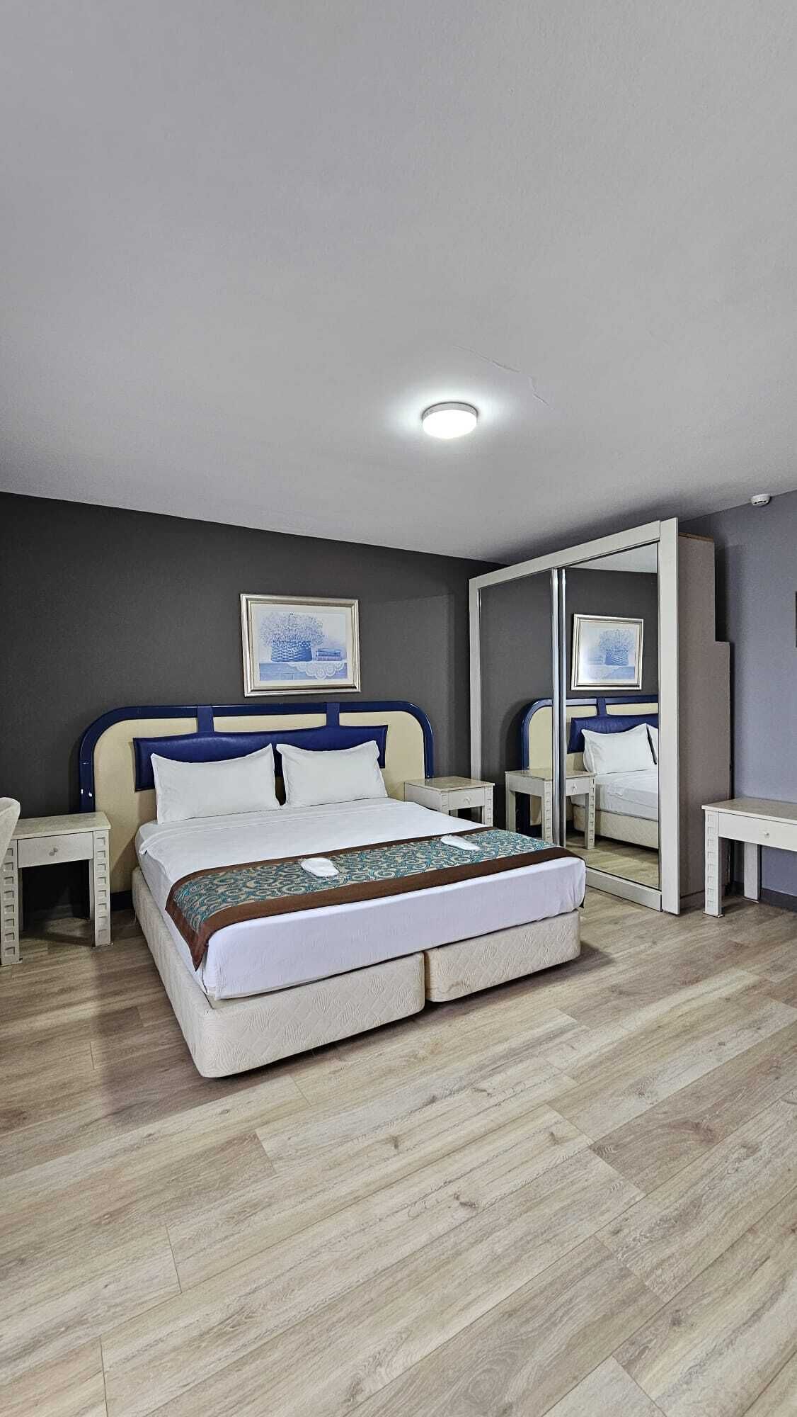 Ein Hotelzimmer mit Doppelbett, Nachttischen, einem Kleiderschrank und einer Deckenleuchte.