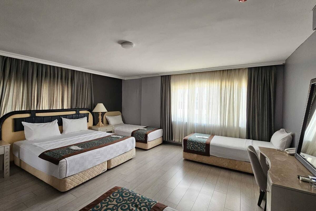 A hotel room with a large bed, a smaller bed, a desk, a chair, and a mirror.