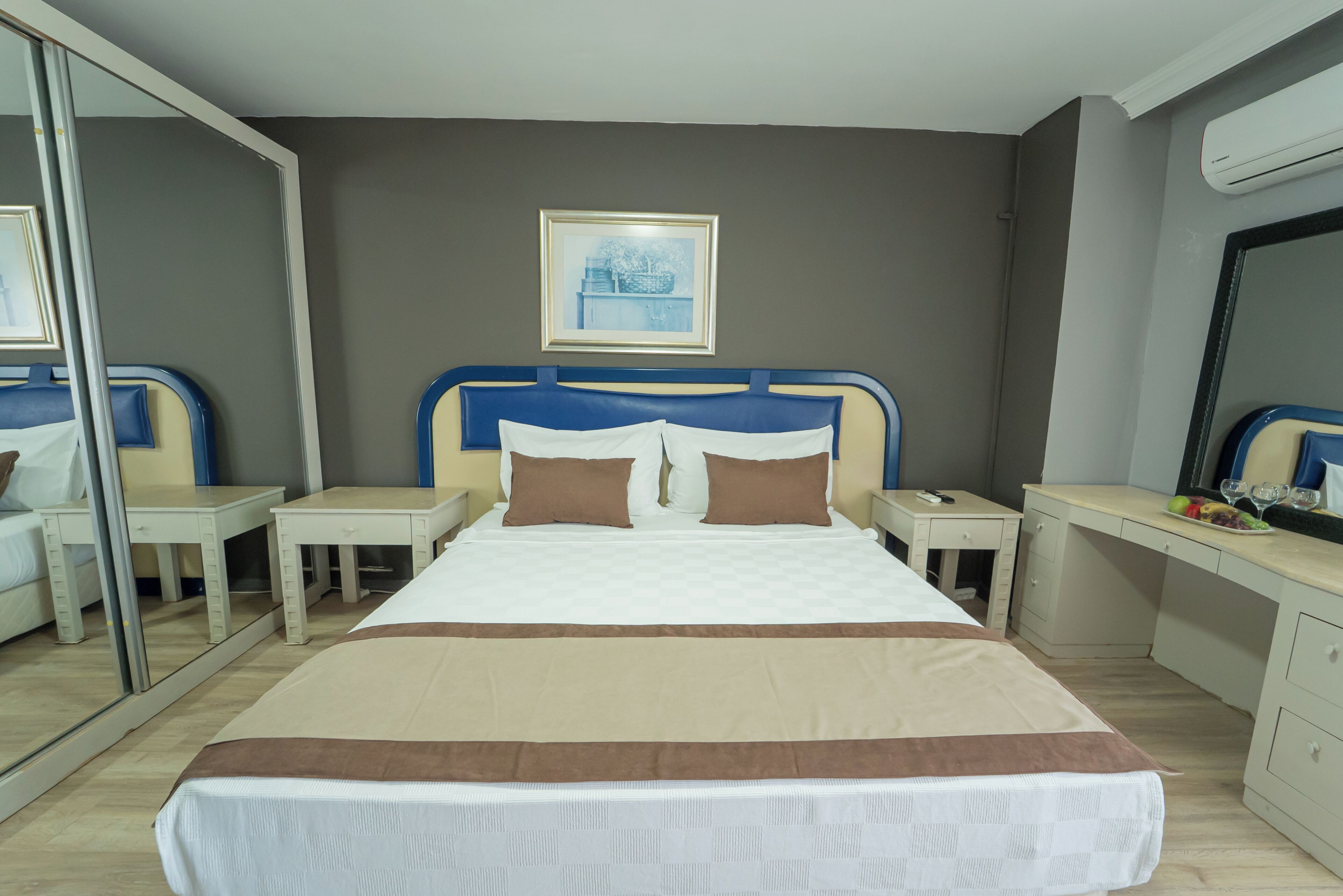Habitació d'hotel amb un llit, taules de nit, escriptori i un mirall.