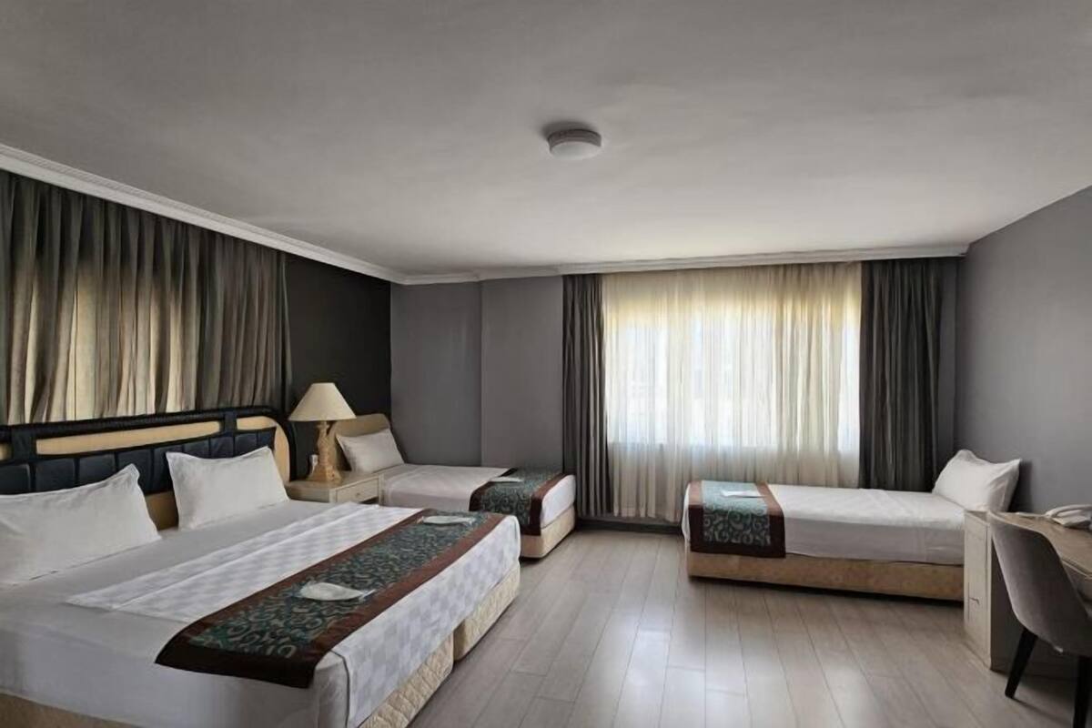 A hotel room with two single beds, a desk, and a chair.