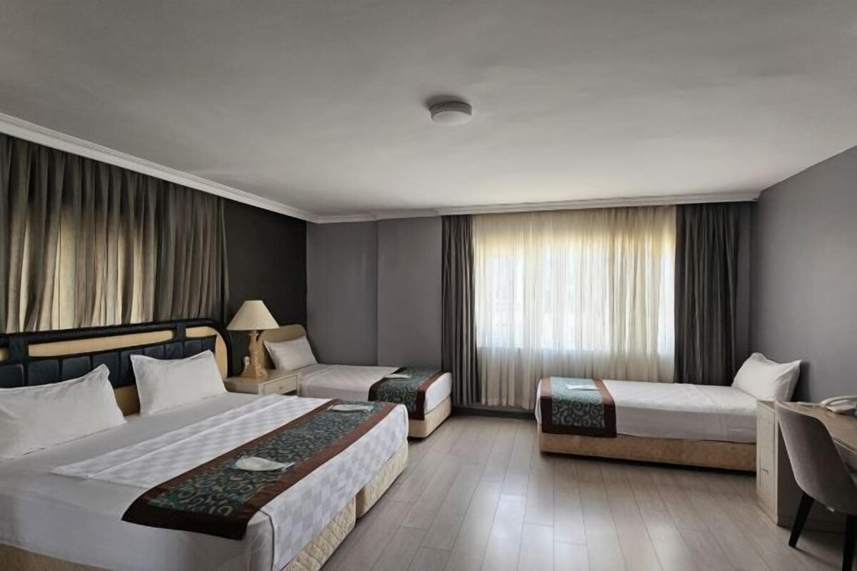 A hotel room with two single beds, a desk, and a chair.