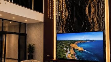 A modern living room with a large flat-screen TV, comfortable seating, and decorative lighting.