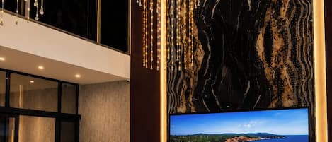 Una sala de estar moderna con un televisor de pantalla plana grande, asientos cómodos e iluminación decorativa.