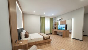 Una habitació d'hotel moderna amb un llit, una taula de treball, una televisió i una cadira.