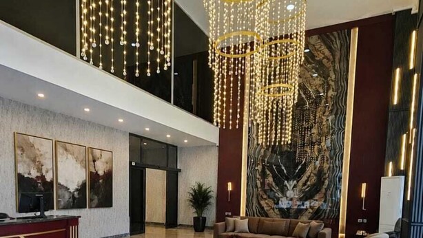 Un vestíbul ampli amb un taulell de recepció, un sofà gran i una paret decorativa.