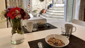 Une table à manger avec un vase de fleurs, un bol de céréales et une tasse.