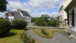 A residential area with a paved courtyard, a small bridge, and houses with white walls and dark roofs. - Holiday Home in Guerlesquin near Lake (Guerlesquin)