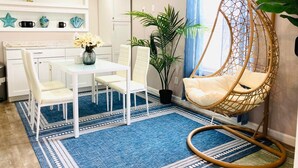 A modern kitchen with white cabinets, a dining table with chairs, a hanging chair, and a blue patterned rug. - Private Apartment with private entrance, Full Bathroom, Living room, Kitchen (Cranston)