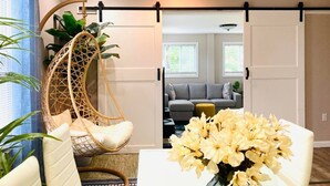 A modern living room with a hanging chair, a white sofa, and a table with a vase of flowers. - Private Apartment with private entrance, Full Bathroom, Living room, Kitchen (Cranston)