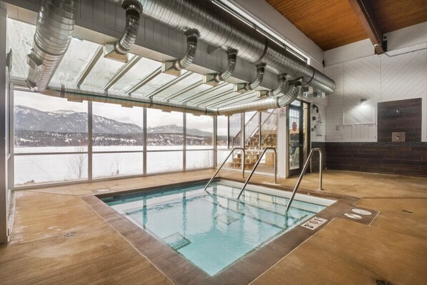 An indoor swimming pool with clear views of mountains and a snowy landscape through large windows. - Cottage Culture | Indoor Pool & Hot Tub | Beach (Windermere)