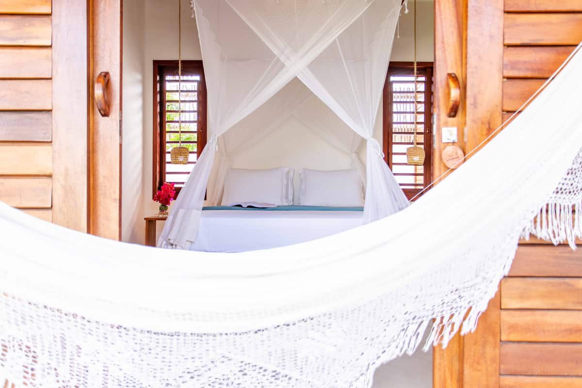 Una cama con dosel blanco, paredes de madera y una ventana con persianas.