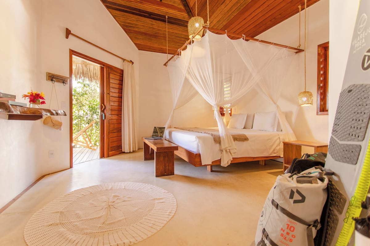 Un dormitorio con cama, cabecera de madera, mesita de noche y lámpara colgante.