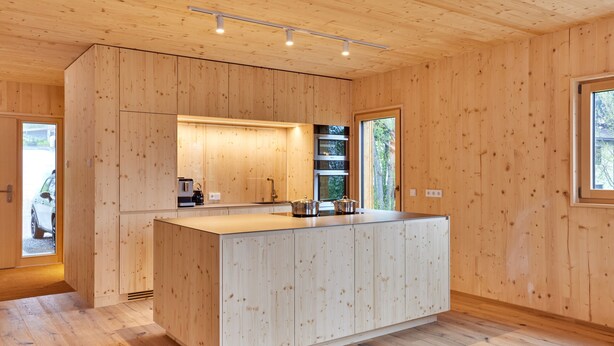 A modern kitchen with wooden cabinetry, a large island, and built-in appliances.