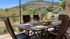 Un espace de restauration en plein air avec une table dressée pour quatre personnes, entourée de chaises, offrant une vue panoramique sur une colline pittoresque.