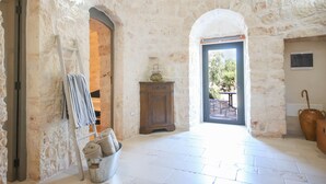 A stone-walled room with a wooden cabinet, a ladder, and a basket of rolled towels. - TD Trulli Albapetra Pool & Olive Trees (Polignano a Mare)