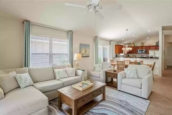 Relax in this inviting living area with a sofa set, dining table, and kitchen in the background.