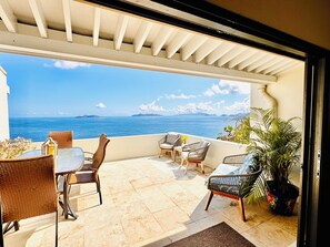A balcony with wicker furniture, a potted plant, and a view of the sea.