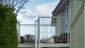 Ein Wohngebäude mit geschlossenem Eingangsbereich, einem kleinen Balkon und einer Treppe zum Eingang.