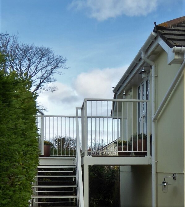 Un edificio residencial con entrada porticada, un pequeño balcón y una escalera que lleva a la entrada.