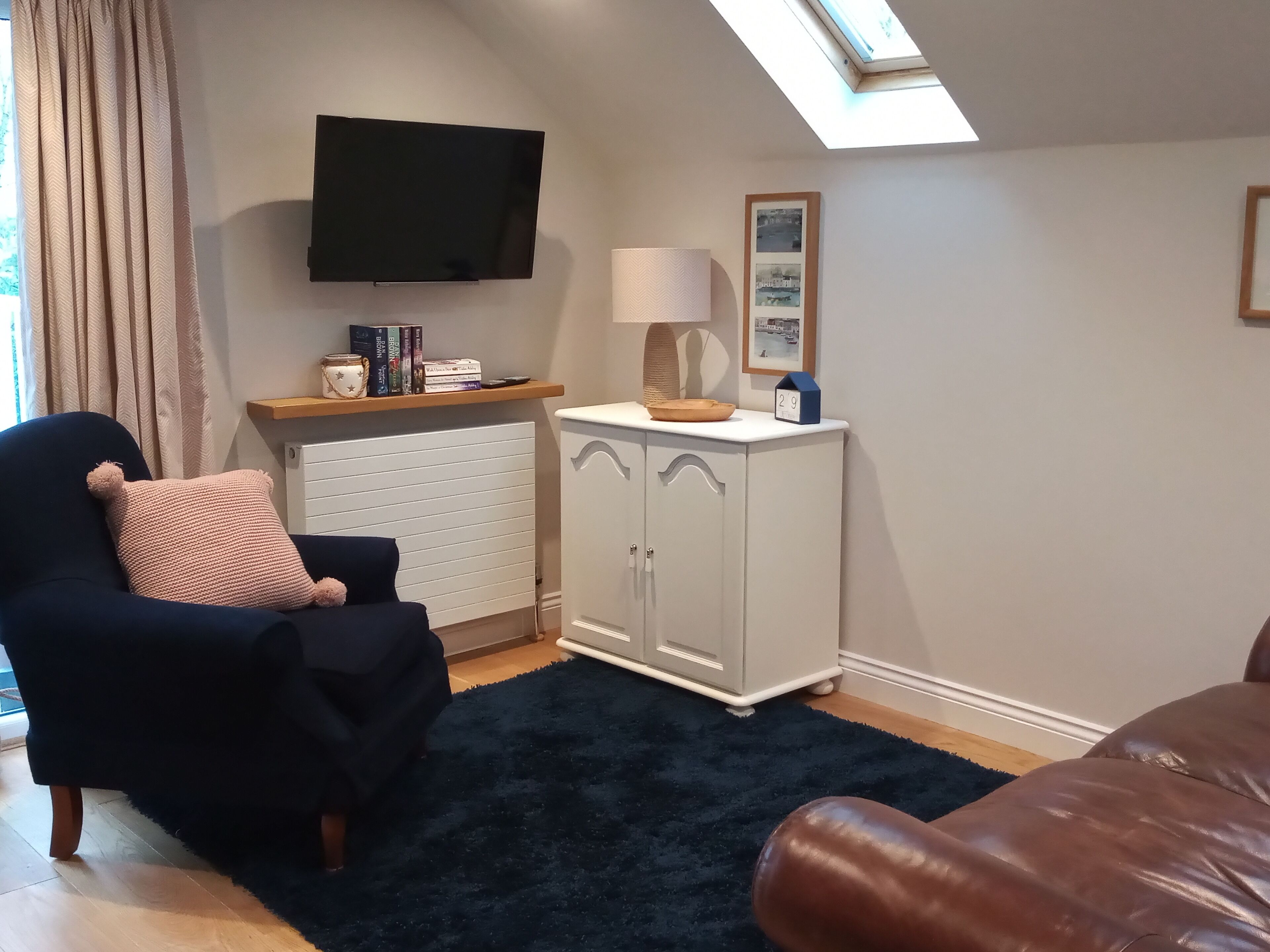 Una sala de estar con un sofá, un televisor, un mueble y una alfombra.