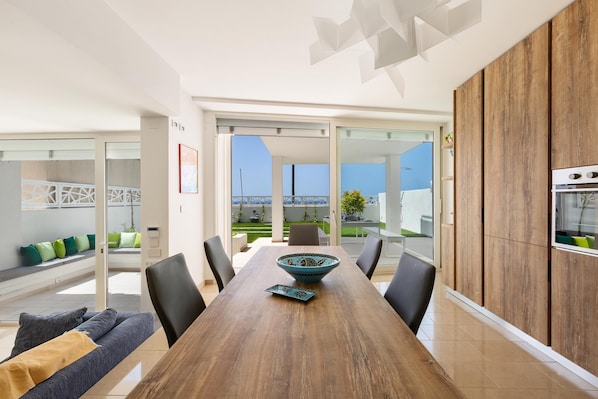 A modern kitchen with a wooden dining table, black chairs, and a decorative bowl.