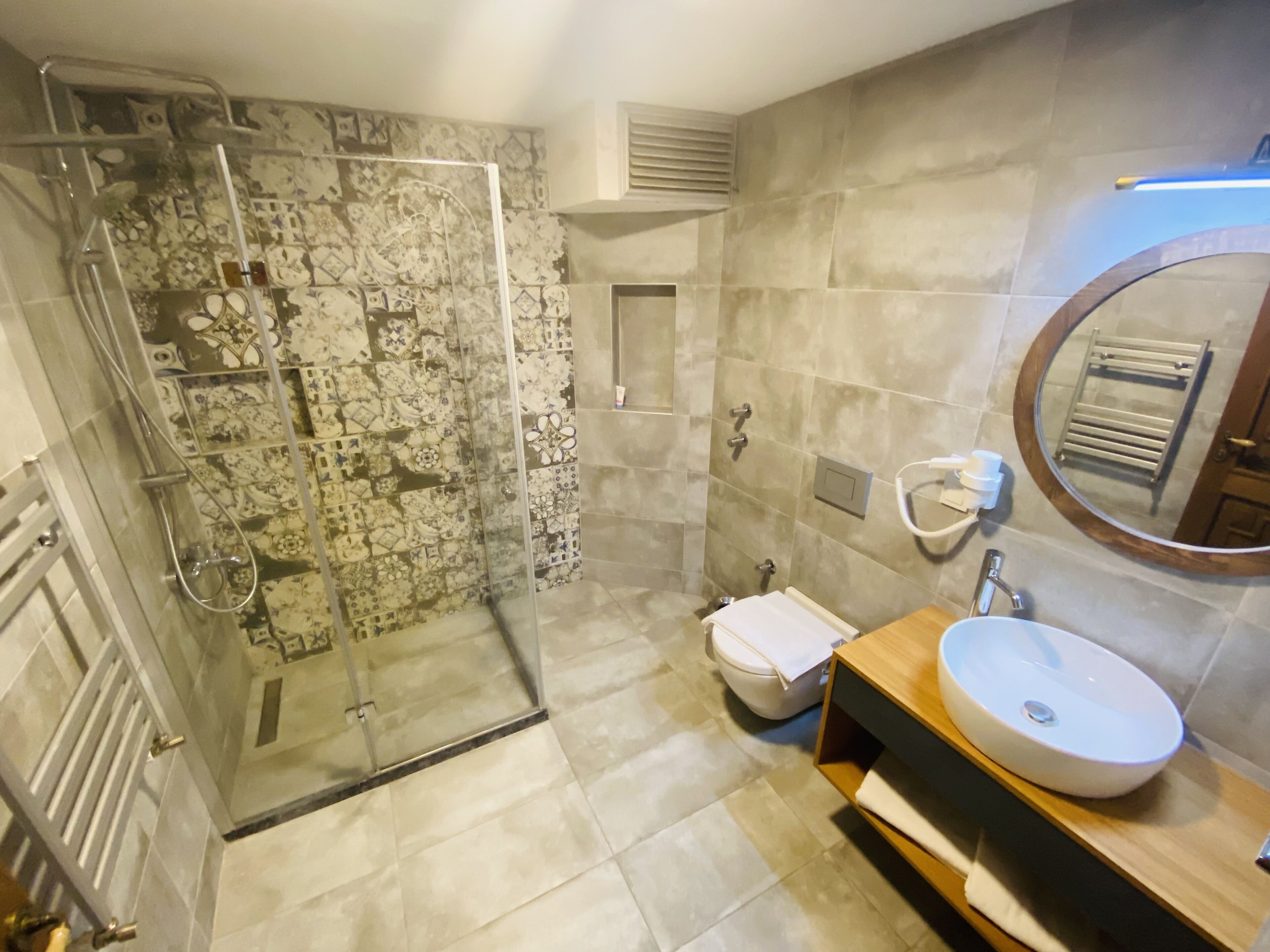 A bathroom with a glass-enclosed shower, a toilet, a sink, and a mirror.