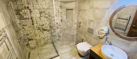 A bathroom with a glass-enclosed shower, a toilet, a sink, and a mirror.