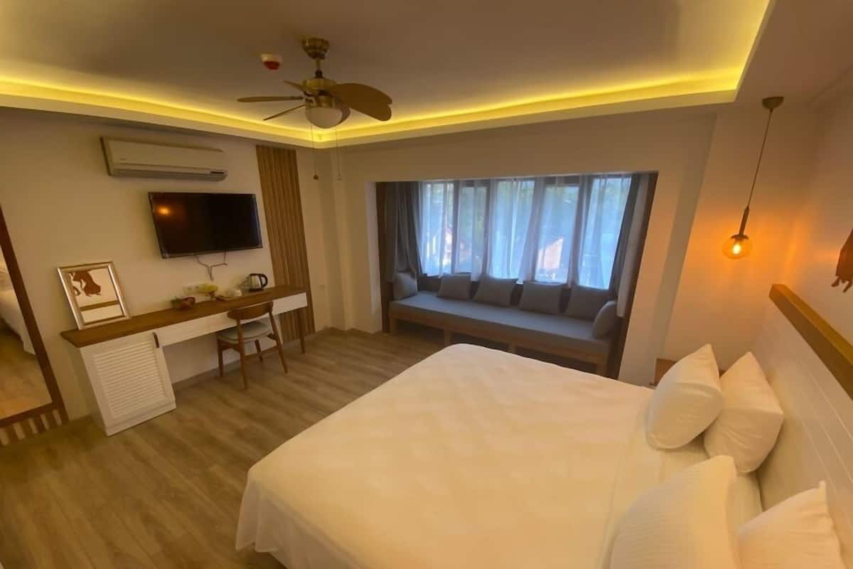 A hotel room with a bed, a desk, a TV, and a window with a view.