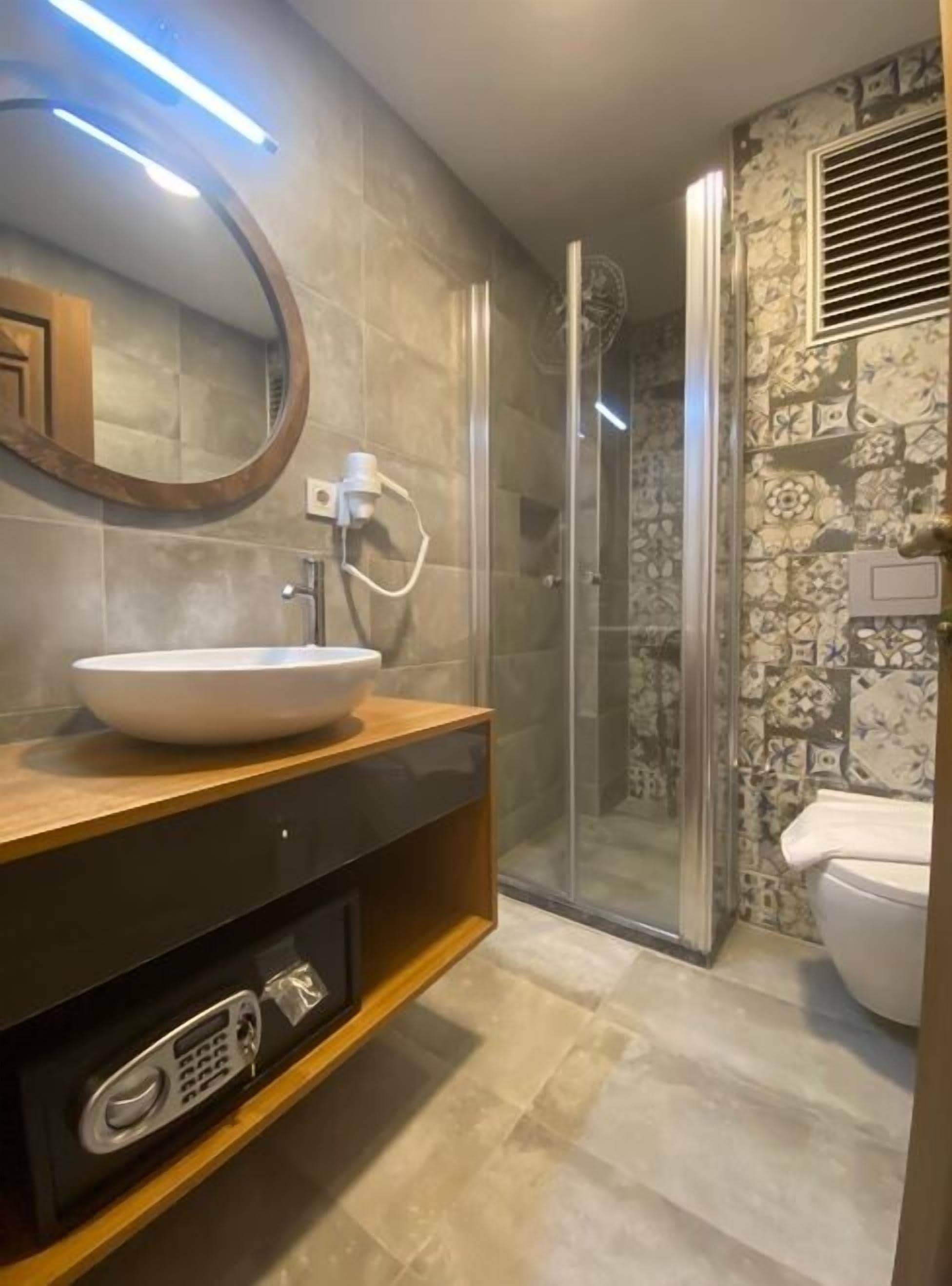 Une salle de bain moderne avec un grand miroir, un lavabo blanc et une cabine de douche.