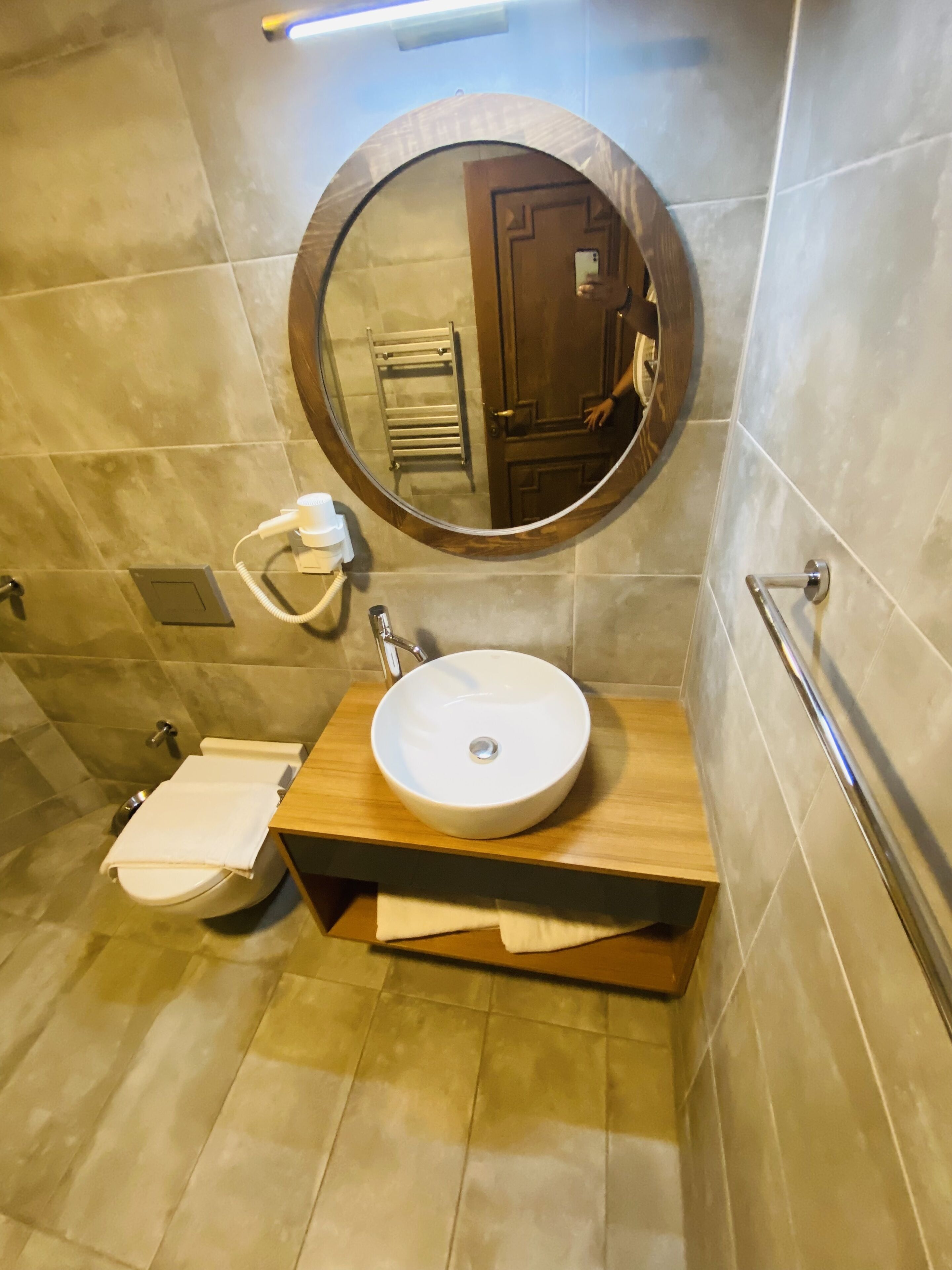 A bathroom with a round mirror, a sink, and a towel rack.