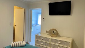 Une chambre avec un lit, une commode, un décor à thème marin et un téléviseur fixé au mur.