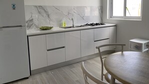 Une cuisine moderne avec des armoires blanches, un pare-feu en marbre, une cuisinière encastrée et une fenêtre.