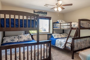 A bunk bed room with a ceiling fan, a window with a view, and a small table.