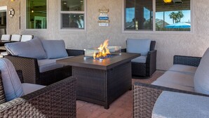 An outdoor seating area with wicker furniture and a central fire feature.