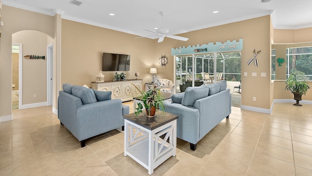 A spacious living room with two grey sofas, a coffee table, and a TV. - Canal Waterfront Home with heated private pool (Palm Coast)