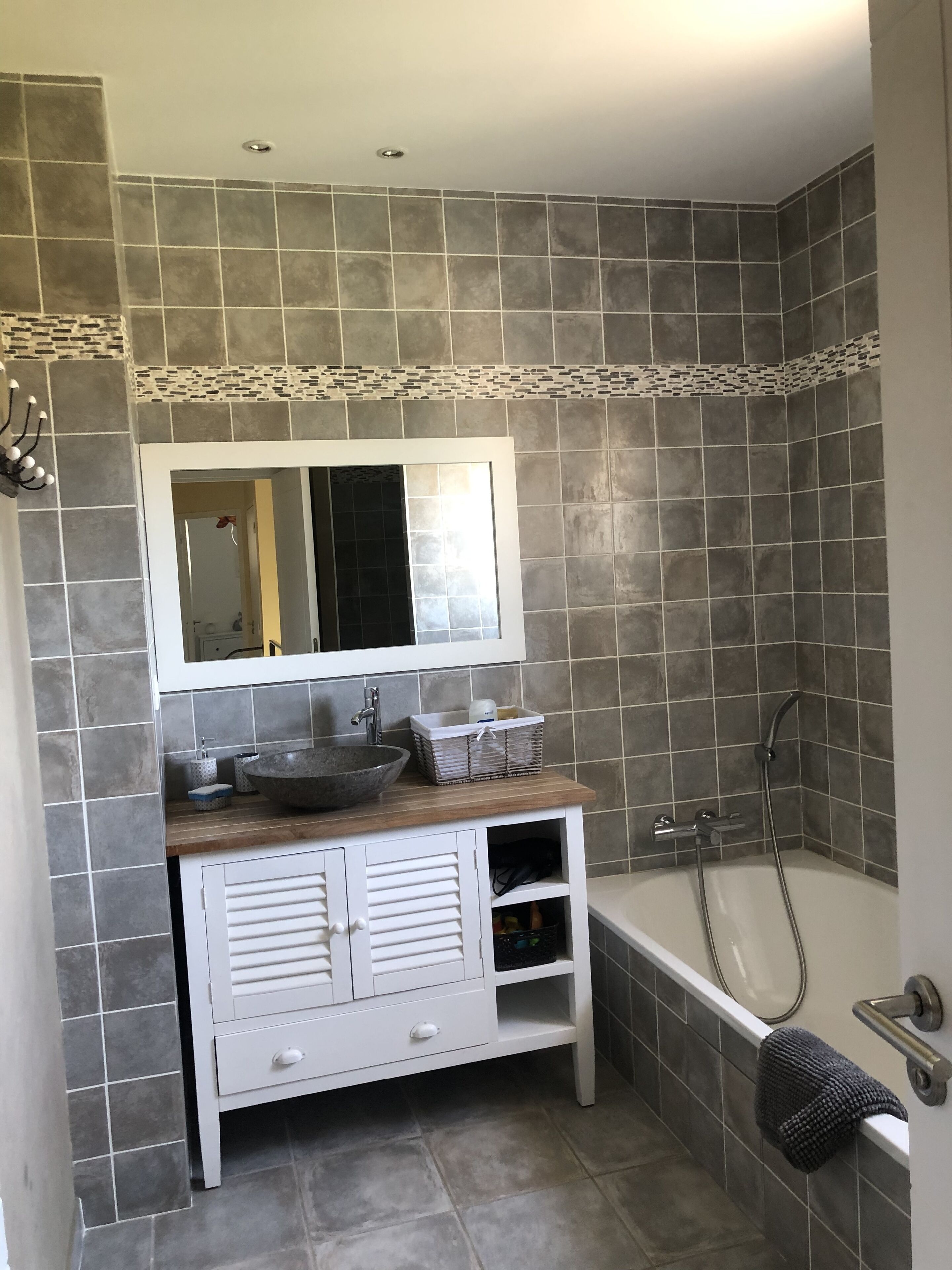 Casa de banho com lavatório, espelho e chuveiro.