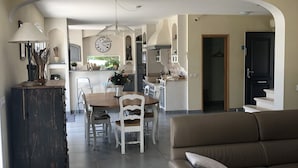 Ein geräumiger Wohnbereich mit Sofa, Esstisch und einer Küche im Hintergrund.
