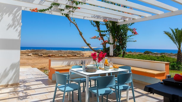 Terraza con mesa lista para comer, con vistas a la playa.