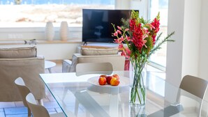 Un moderno comedor con una mesa de vidrio, sillas y un jarrón de flores.