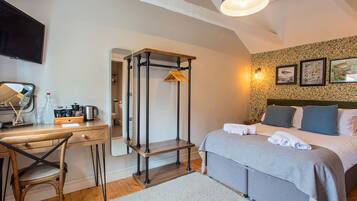 Un dormitorio con cama, mesita de noche, silla, escritorio y espejo.